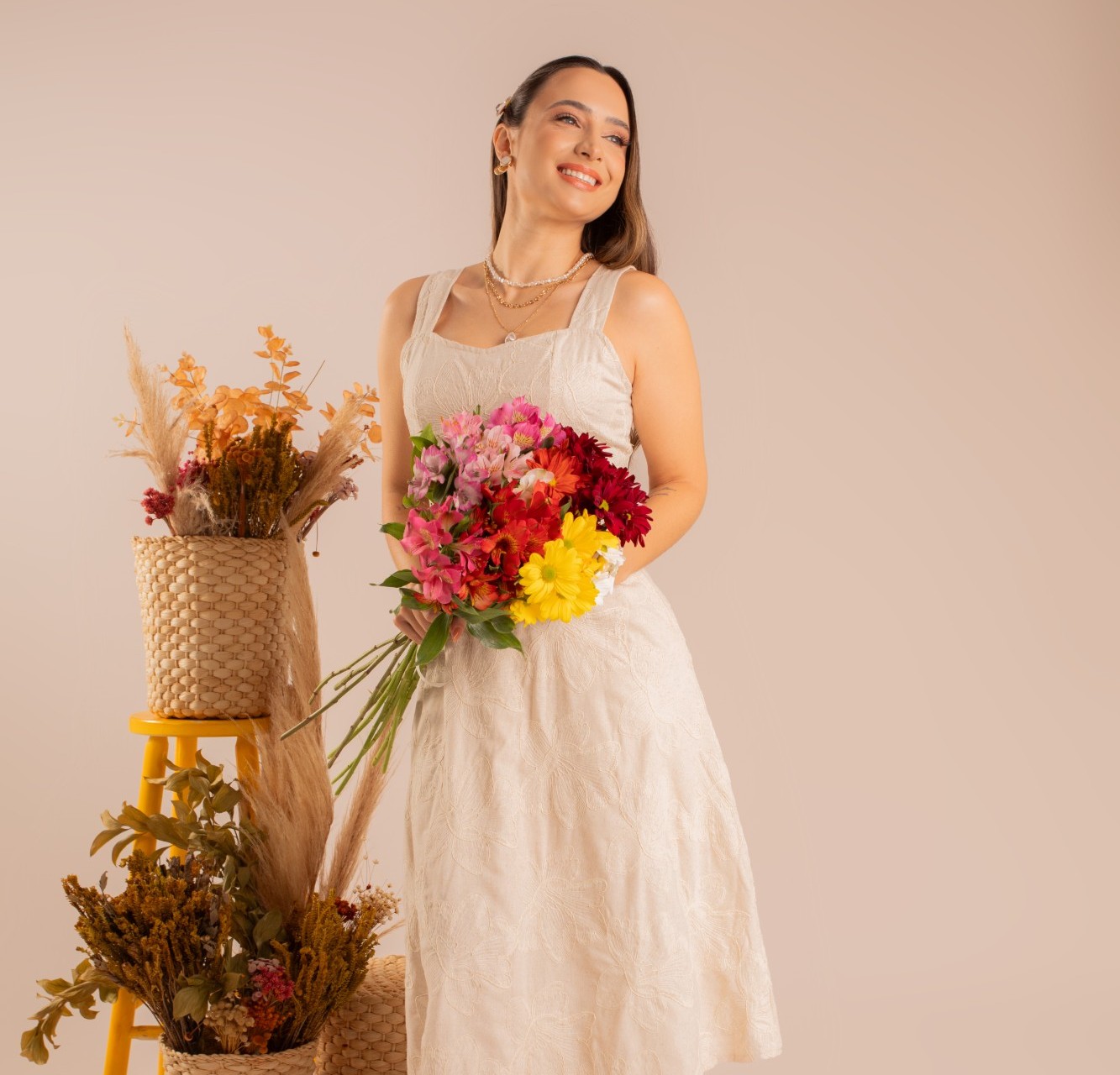 Modelo com vestido bordado off-white segurando buquê colorido