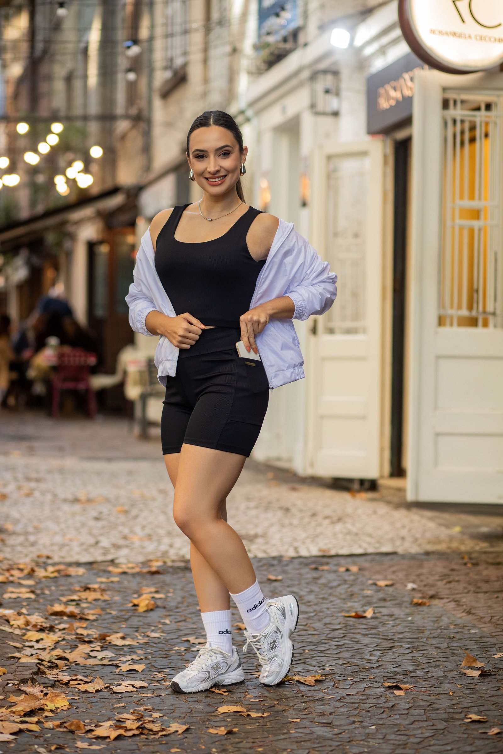 Conjunto fitness preto com corta-vento branco na rua