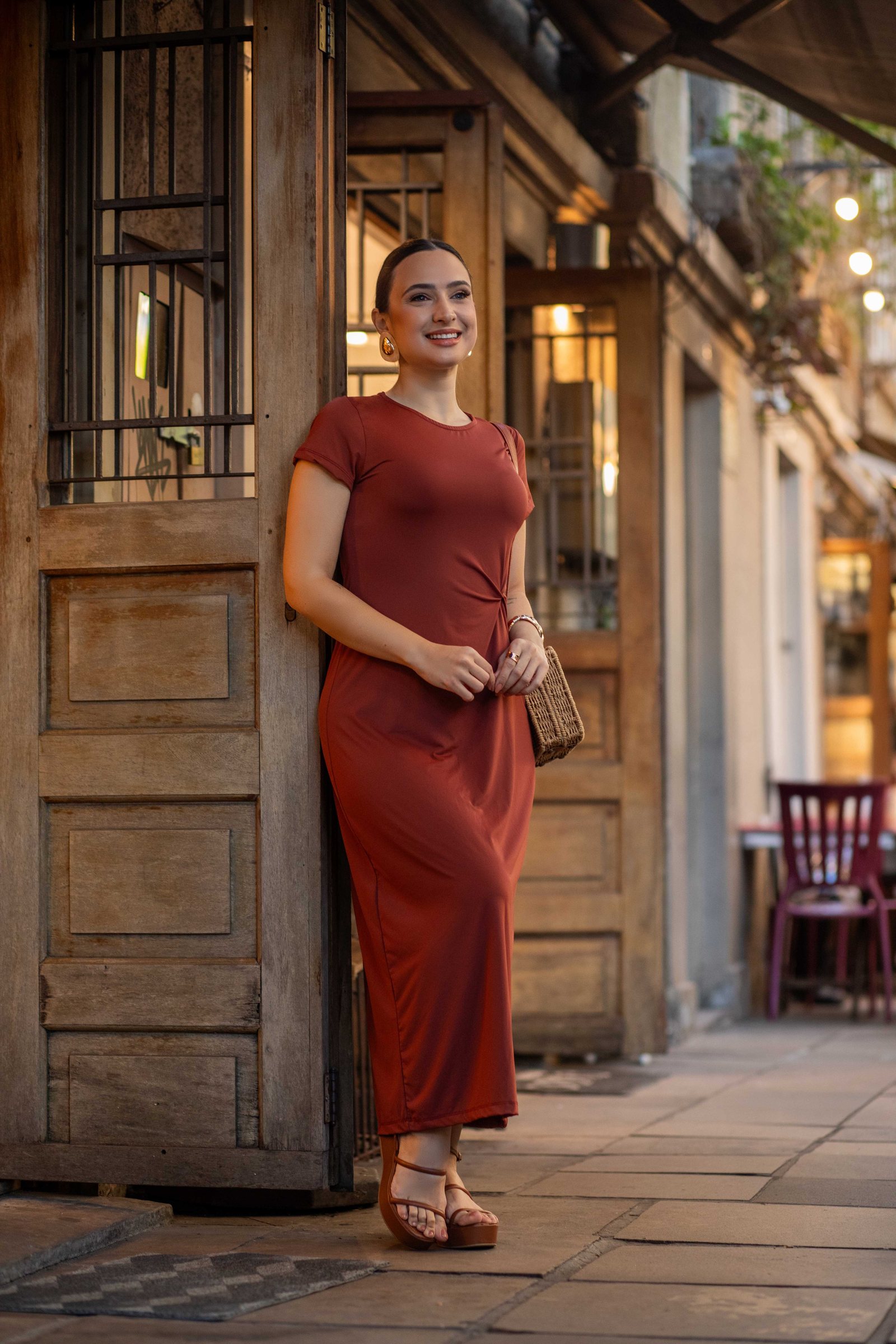Vestido terracota encostada em porta de madeira